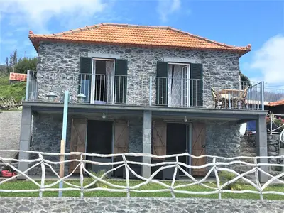 a stone house with a fence in front of it at Casa dos Reis in Calheta