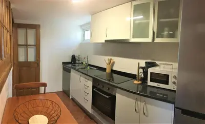 a kitchen with white cabinets and a black counter top at Casa dos Reis in Calheta