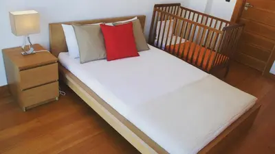 a crib with a red pillow and a night stand at Villa Cary in Funchal