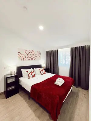 a bedroom with a large bed with a red blanket at Gardens Guest House in São Vicente