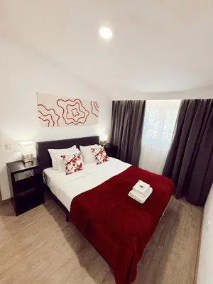 a bedroom with a large bed with a red blanket at Gardens Guest House in São Vicente