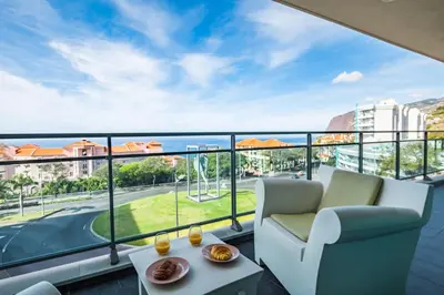 a room with a view of the ocean from a balcony at Apartamento Monumental - By WeHost Madeira in Funchal