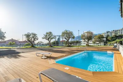a large swimming pool with chairs on a wooden deck at Apartamento Monumental - By WeHost Madeira in Funchal