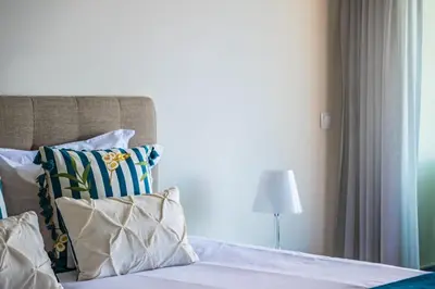 a bedroom with a bed with pillows and a lamp at Apartamento Monumental - By WeHost Madeira in Funchal
