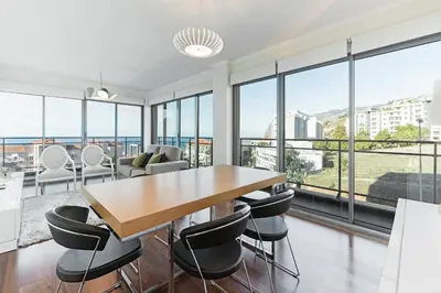 a dining room with a table and chairs and large windows at Apartamento Monumental - By WeHost Madeira in Funchal
