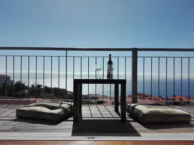 a table with a bottle and wine glass on a balcony at Zen Caniço Apartment in Caniço