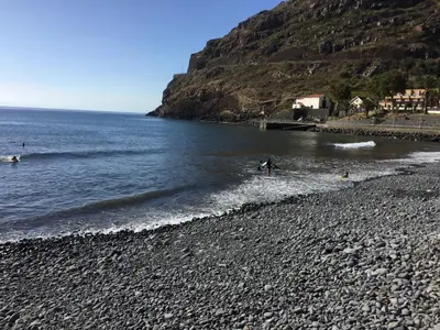 a group of people playing in the water on a rocky beach at Estacada Apartment in Machico