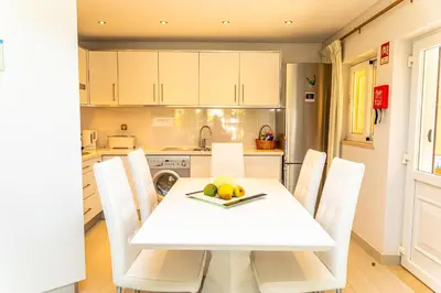 a kitchen with a white table and white chairs at Resort Fazenda Viegas in Lagos