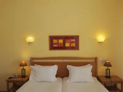 a bedroom with two beds with white pillows and two lamps at Club House CVL in Luz
