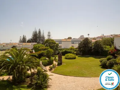 a garden with palm trees and a sign that says clean and safe at Club House CVL in Luz