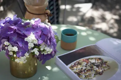 a table with a vase of purple flowers and a book at Irlandas Villa Funchal Seaside Villas in Funchal