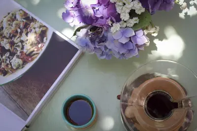 a table with a vase of flowers and a cup of coffee at Irlandas Villa Funchal Seaside Villas in Funchal