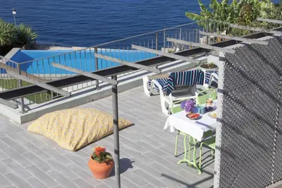 a balcony with a table and chairs and the water at Irlandas Villa Funchal Seaside Villas in Funchal