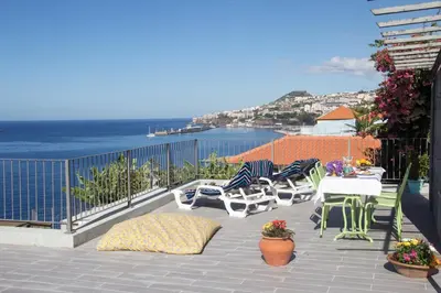 a patio with chairs and tables and a view of the ocean at Irlandas Villa Funchal Seaside Villas in Funchal