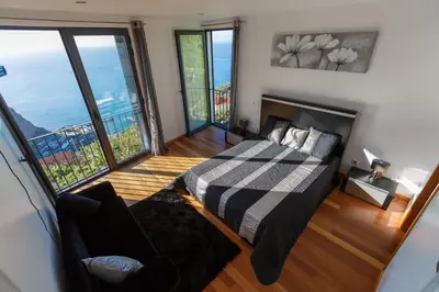 a bedroom with a bed in a room with large windows at Villa Maciel in Calheta