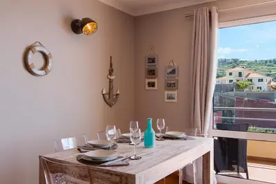 a dining room with a table with glasses and a window at Peace Haven in Calheta
