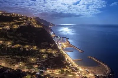 an aerial view of a city with the ocean at night at Peace Haven in Calheta