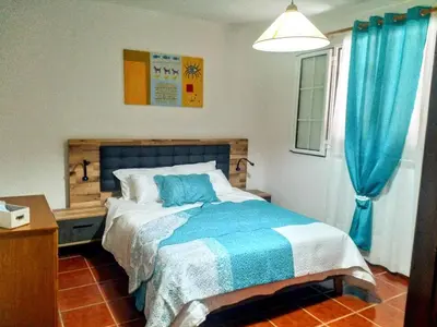 a bedroom with a bed and a blue curtain at Refugio das Matas in Porto Santo