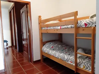 a room with two bunk beds and a hallway at Refugio das Matas in Porto Santo