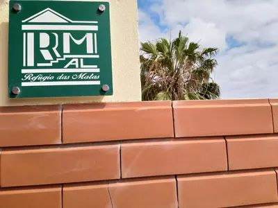 a sign on the side of a brick wall at Refugio das Matas in Porto Santo
