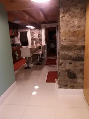 a living room with a stone wall and a piano at Vila Vinha in Arco da Calheta