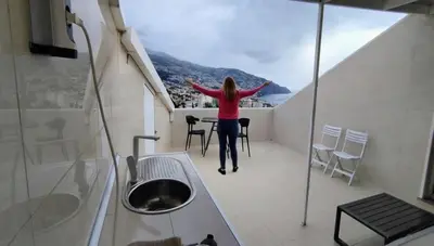 a woman standing on a balcony with her arms out at Colinas do Sol in Funchal