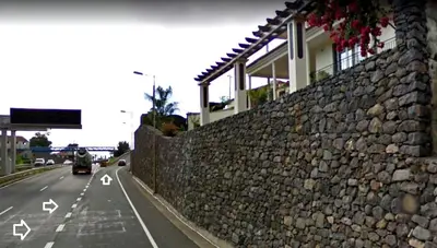 a car driving down a road next to a stone wall at Colinas do Sol in Funchal