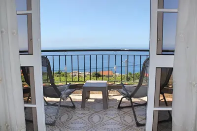 a balcony with a table and chairs and a view of the ocean at OurMadeira - Casa Vista Bela in Estreito da Calheta