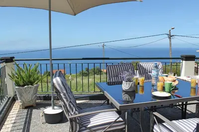 a table and chairs on a balcony with a view of the ocean at OurMadeira - Casa Vista Bela in Estreito da Calheta