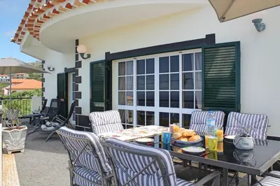 a patio with a table and chairs and a window at OurMadeira - Casa Vista Bela in Estreito da Calheta