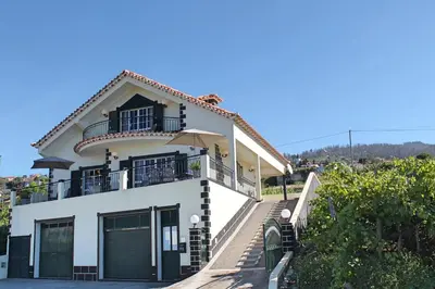 a white house with a balcony on top of it at OurMadeira - Casa Vista Bela in Estreito da Calheta