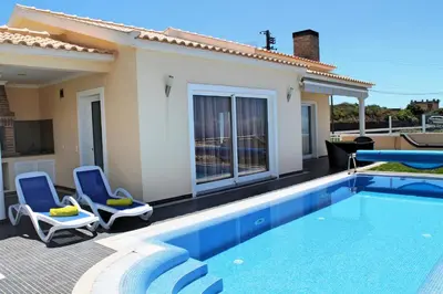 a swimming pool with two chairs and a house at Tranquil villa with pool in Calheta ArcoView in Calheta