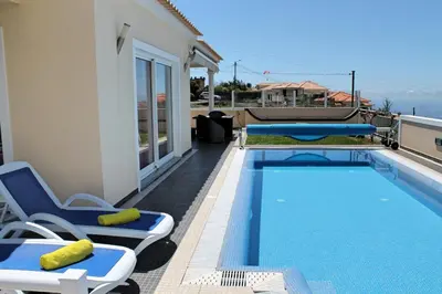 a swimming pool with two lounge chairs next to a house at Tranquil villa with pool in Calheta ArcoView in Calheta