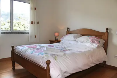 a bedroom with a bed with white sheets and a window at Tranquil villa with pool in Calheta ArcoView in Calheta