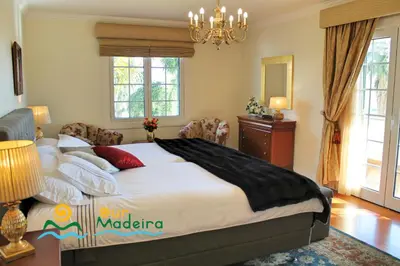 a bedroom with a large bed and a chandelier at OurMadeira - Villa Luzia in Funchal