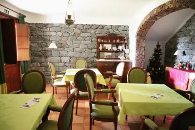 a restaurant with tables and chairs and a stone wall at Casa D'Avo Beatriz in Gaula
