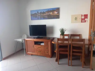 a living room with a television and a table and chairs at Vilas Horizonte in Porto Santo
