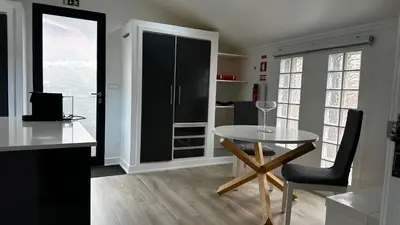 a kitchen with a table and a chair in a room at Maison Blanche in Arco da Calheta