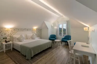 a bedroom with a bed and two blue chairs at OurMadeira - Babosas Village in Funchal