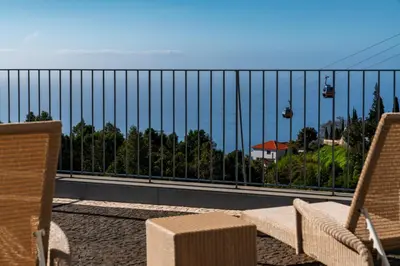 a balcony with two chairs and a view of the ocean at OurMadeira - Babosas Village in Funchal