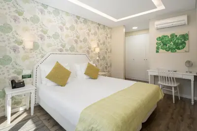 a bedroom with a white bed and a desk at OurMadeira - Babosas Village in Funchal