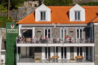 people sitting on a balcony of a building at OurMadeira - Babosas Village in Funchal
