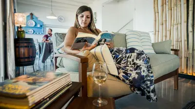 a woman sitting on a couch reading a book at Villa Natura in Vila do Porto
