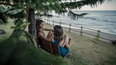 two girls sitting on a bench by the ocean at Villa Natura in Vila do Porto