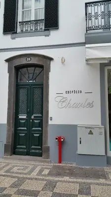 a red fire hydrant in front of a building with a green door at Edifício Charles 203 in Funchal