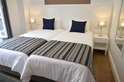 two beds in a small room with two lamps at Edificio Charles 104 in Funchal
