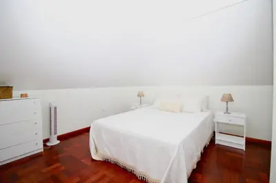 a white bedroom with a white bed and two night stands at Casa Maria in Funchal