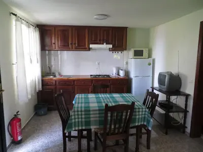 a kitchen with a table and chairs and a white refrigerator at Quinta da quebrada in Santana