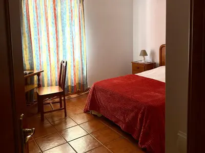 a bedroom with a bed and a chair and a window at Casa do Cisne in Porto Santo