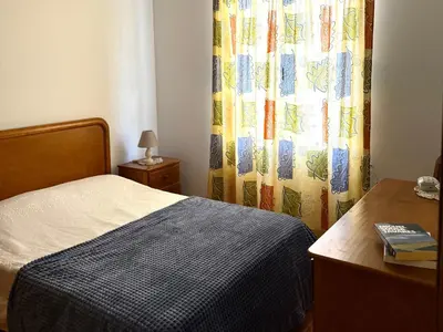 a bedroom with a bed and a table and a curtain at Casa do Cisne in Porto Santo